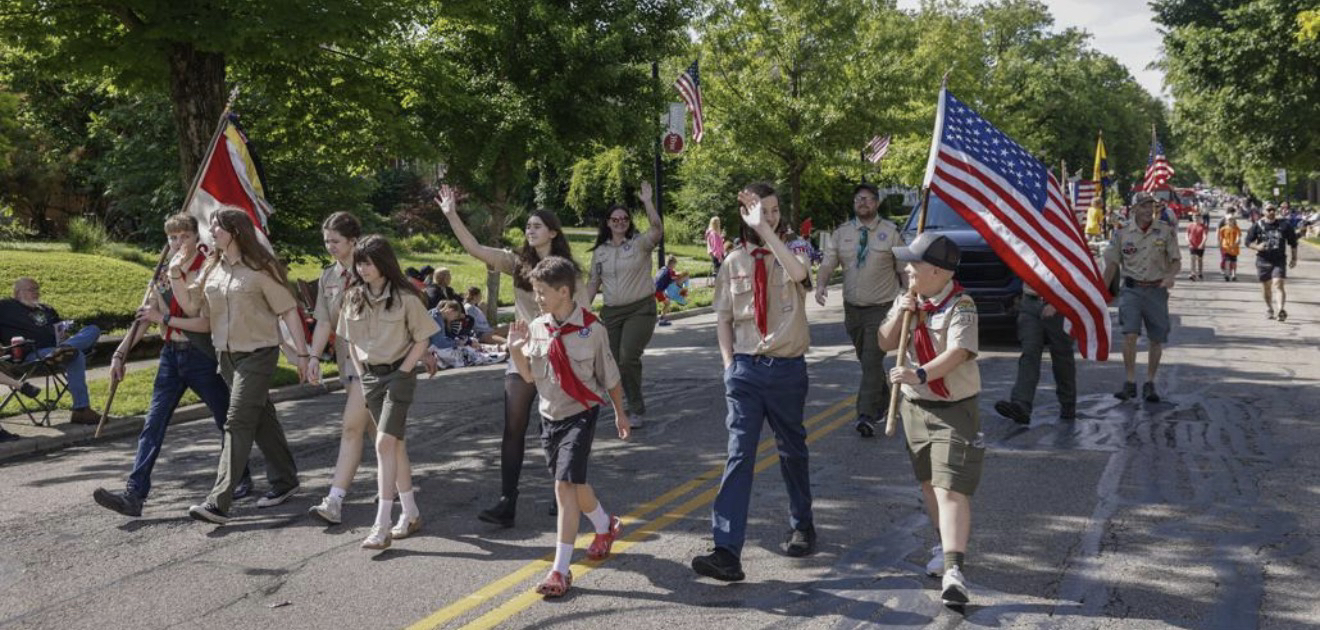 Troop 311 marching in a local parade with flags